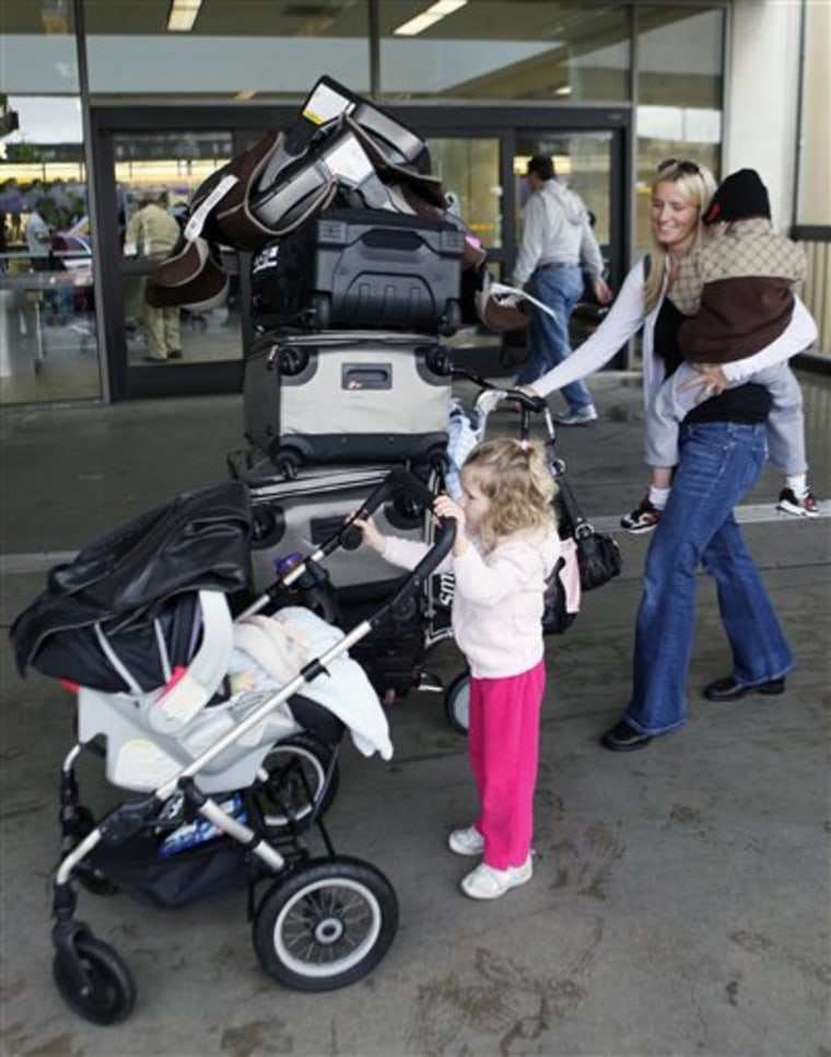 Blair Weisbecker carries her son Kaiden, 4, as her daughter, Makena, pushes her 5-month-old baby brother Lincoln as they line up to check in their luggage at the Los Angeles International Airport in this Dec. 21, 2010, file photo. A airfare "deal" this summer is almost certain to cost more than it did in the last few years. 